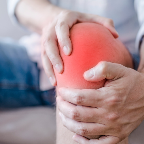 A man with workers compensation knee pain is sitting on a couch. A man with workers compensation knee pain is sitting on a couch.