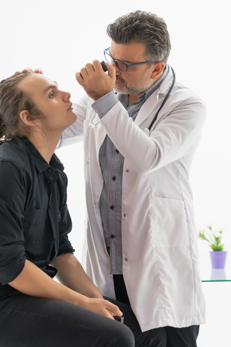 A No-Fault doctor is examining a man's eye.