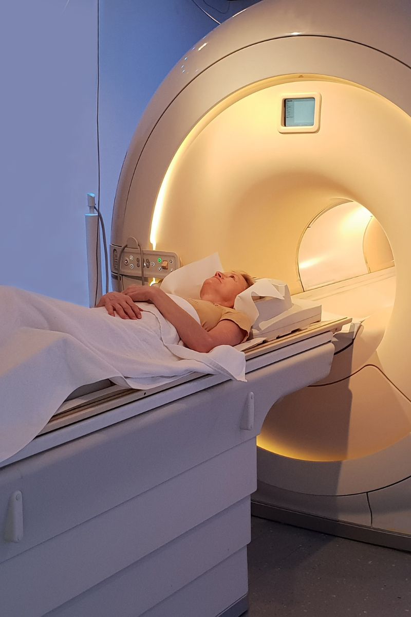 A woman receiving an MRI scan in a hospital bed.