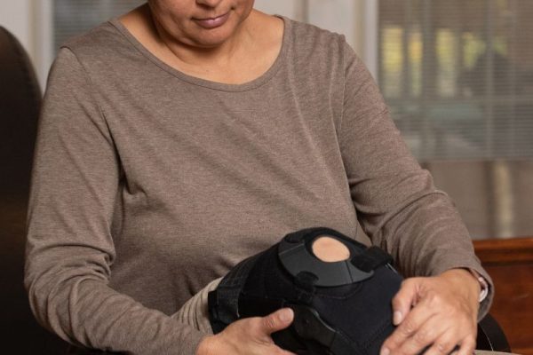 A woman with a knee brace receiving treatment from a Workers Compensation doctor. A woman with a knee brace receiving treatment from a Workers Compensation doctor.