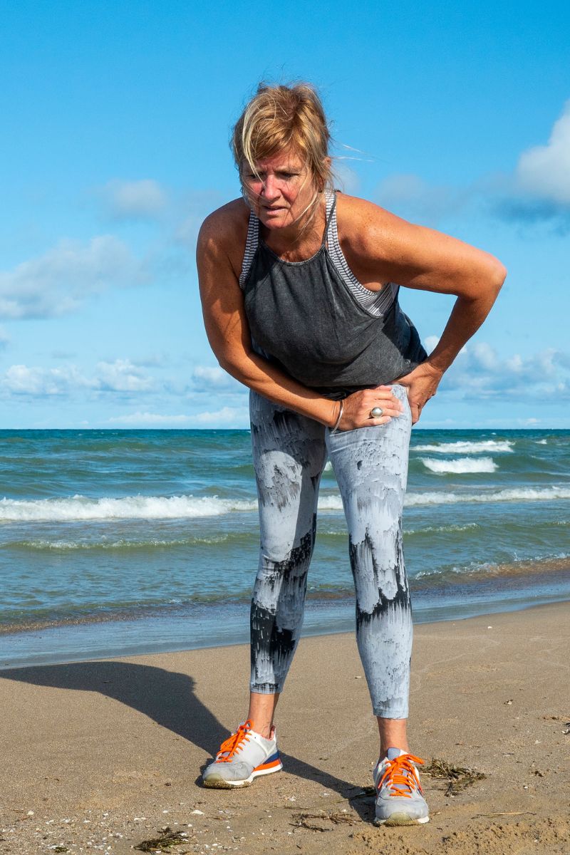 A woman on the beach seeks treatment for her back pain from a No-Fault or Workers Compensation doctor.