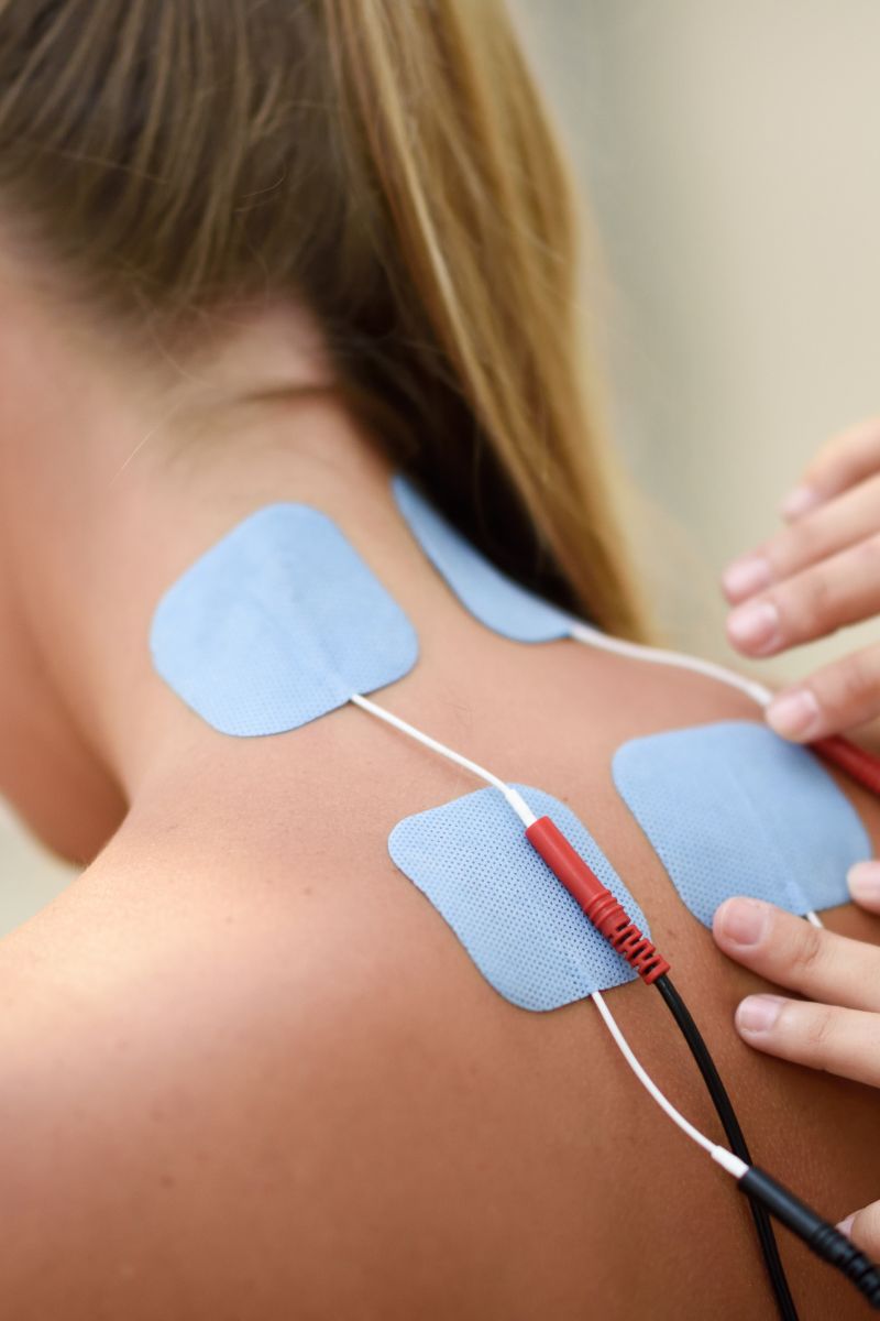 A woman receiving a back treatment at an electrical therapy session conducted by No-Fault doctors.