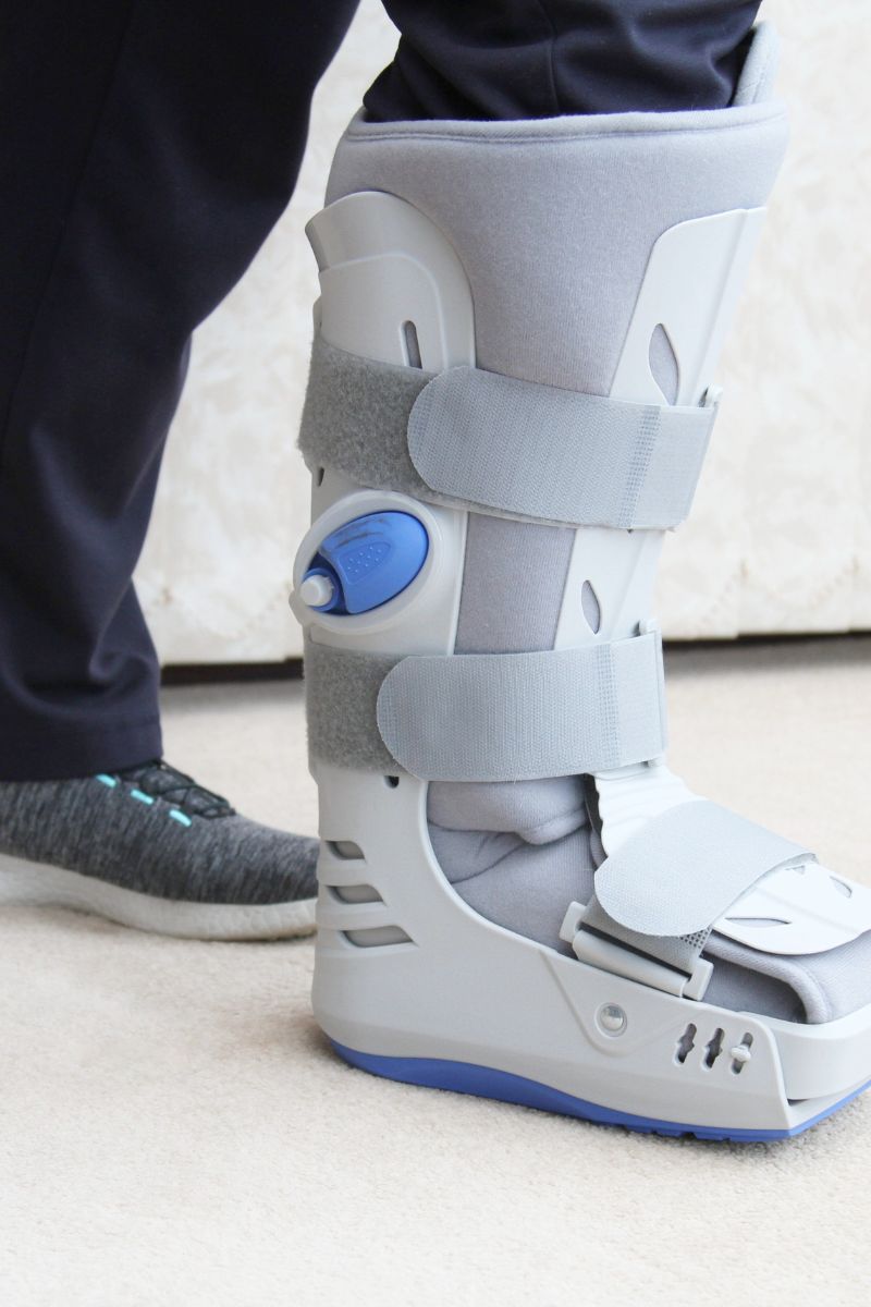 A person wearing a boot with an ankle brace seeks treatment from workers compensation doctors.