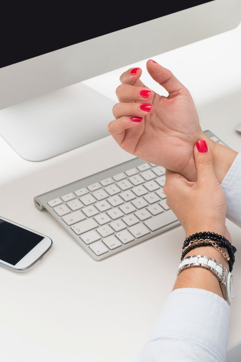 A woman's hand is resting on a computer keyboard in a workplace setting.