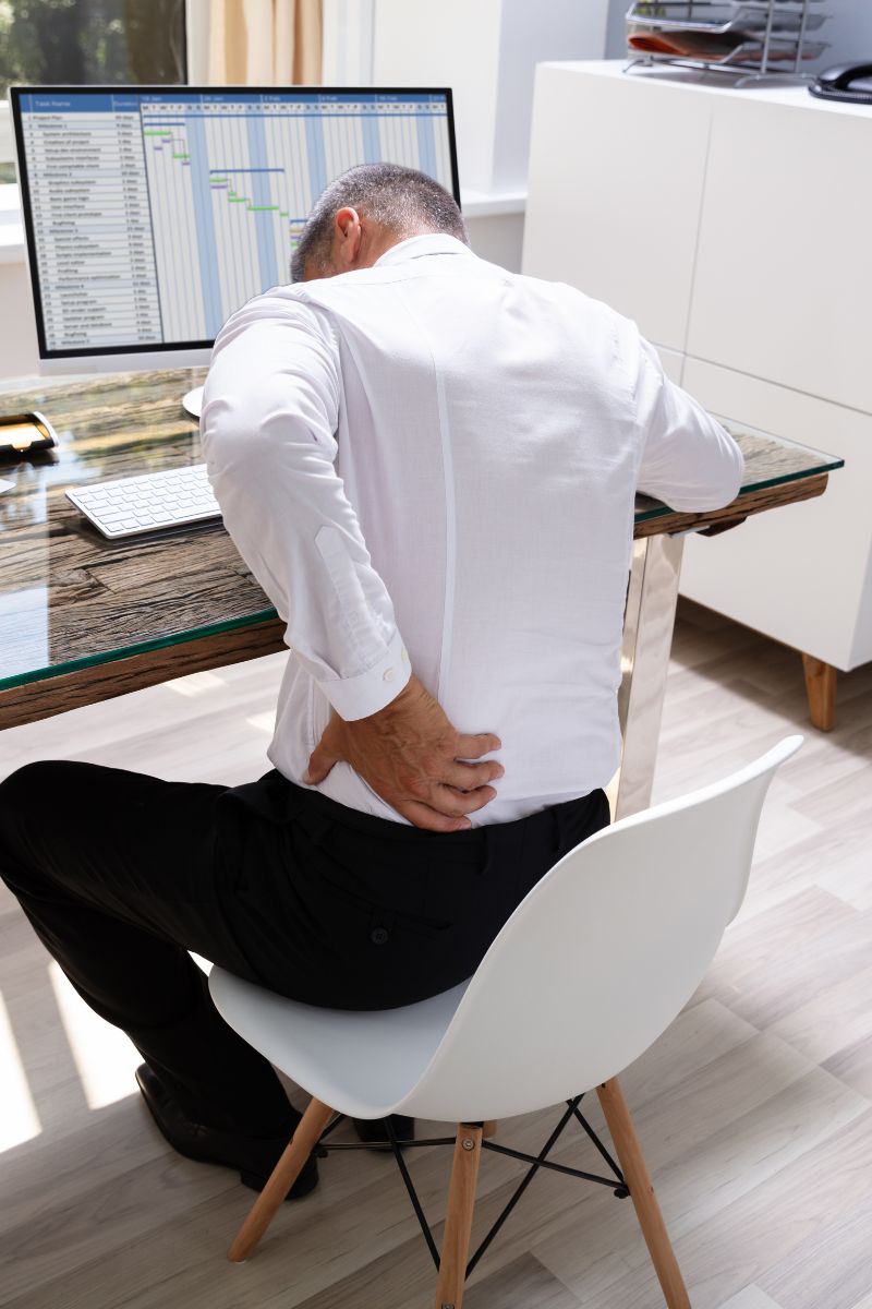 A man experiencing back pain is evaluated by a workers' compensation doctor.