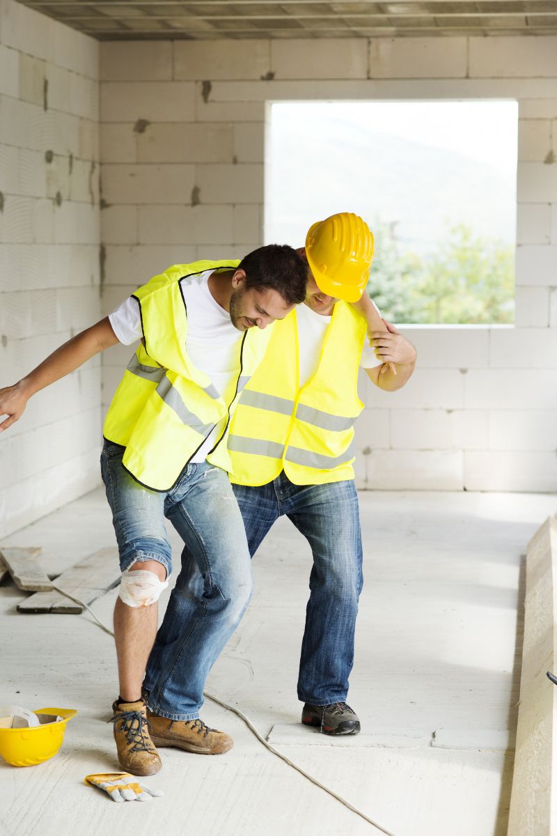 Two construction workers standing on a construction site seeking medical attention from No-Fault doctors specializing in Workers Compensation.