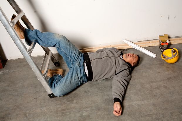 A man laying on the floor next to a ladder with no-fault injuries.