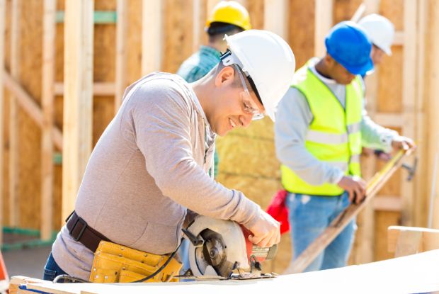 A group of construction workers using a circular saw who are insured by No-Fault and Workers Compensation.