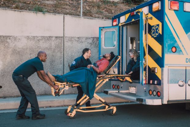 An ambulance transporting a patient on a stretcher, while workers compensation doctors provide necessary medical care.