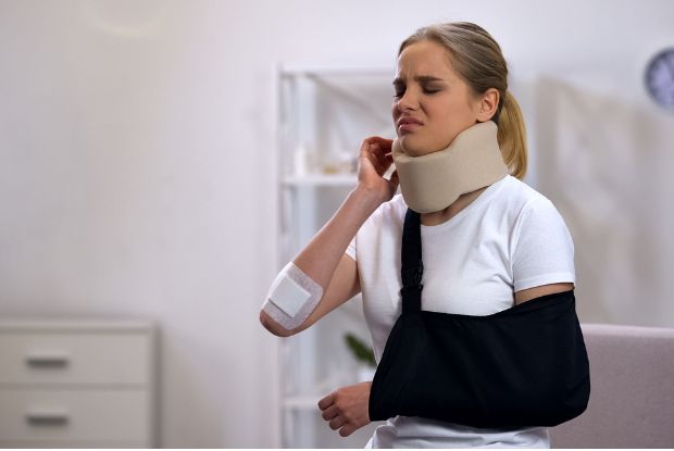 A woman with a neck brace seeks treatment from a no-fault doctor in an office.