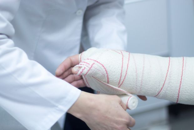 A No-Fault doctor is putting a cast on a patient's arm.