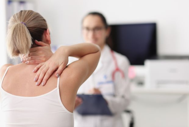 A woman is having her back examined by a No-Fault doctor.