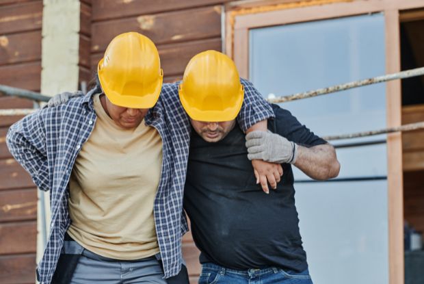 Two construction workers wearing hard hats standing in front of a house, seeking No-Fault & Workers Compensation Doctors.
