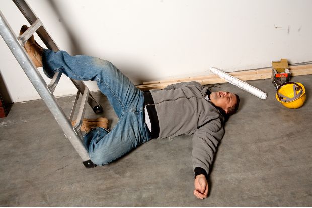 A man lying injured next to a ladder, in need of assessment by workers compensation doctors.