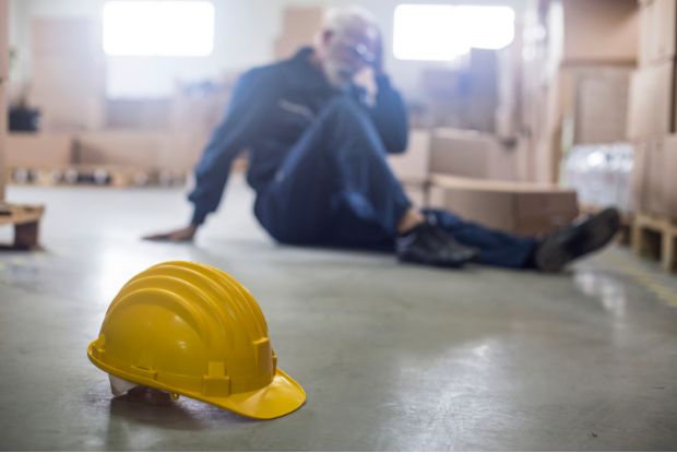 A man sitting on the floor with a hard hat on his head, seeking advice from Workers Compensation Doctors.