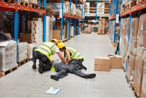 Two workers are resting on the floor in a warehouse.