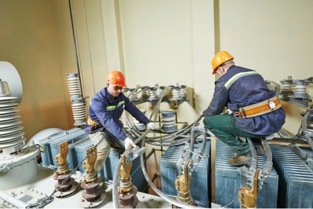 Two electricians working on a transformer in a factory with access to no-fault and workers compensation doctors.