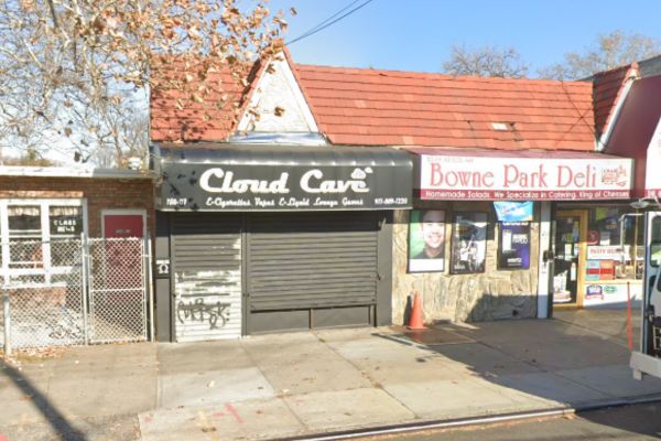 Storefronts with security shutters down, one labeled "Cloud Cave" and an adjacent deli open with advertisements for Workers Compensation Doctors.