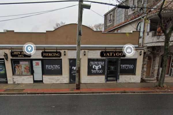Street view of a building with signs for a spa, piercing service, and tattoo shop in Central Islip. A utility pole stands in front, blending into the urban landscape.