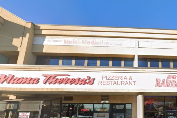 Storefronts in a strip mall in Westbury NY, featuring Mama Theresa's Pizzeria & Restaurant below and Advanced Multi-Medicine & Rehab—home to Workers Compensation Doctors—on the upper level.